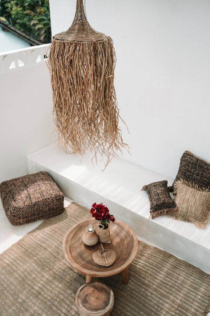 Stijlvolle woonkamer met zeegras tapijt en natuurlijke decoratie, inclusief kussens en lamp, voor een rustieke uitstraling.