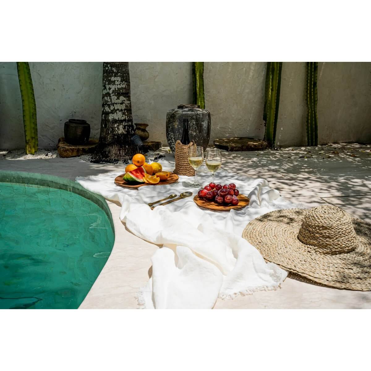 Het witte linnen tafelkleed 150x250cm bij zwembad met fruit en bijpassende servetten, ideaal voor luxe tafelsetting.