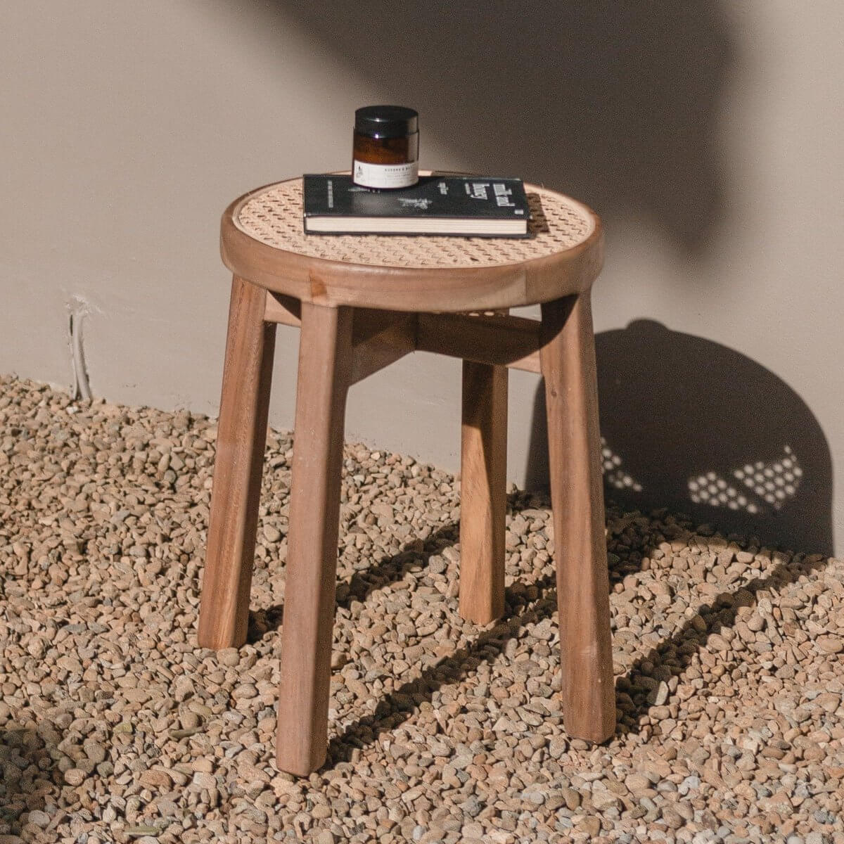 Elegante houten kruk CARAMIN op grind met decoratief boekje en geurige pot voor een warme, natuurlijke uitstraling in je interieur