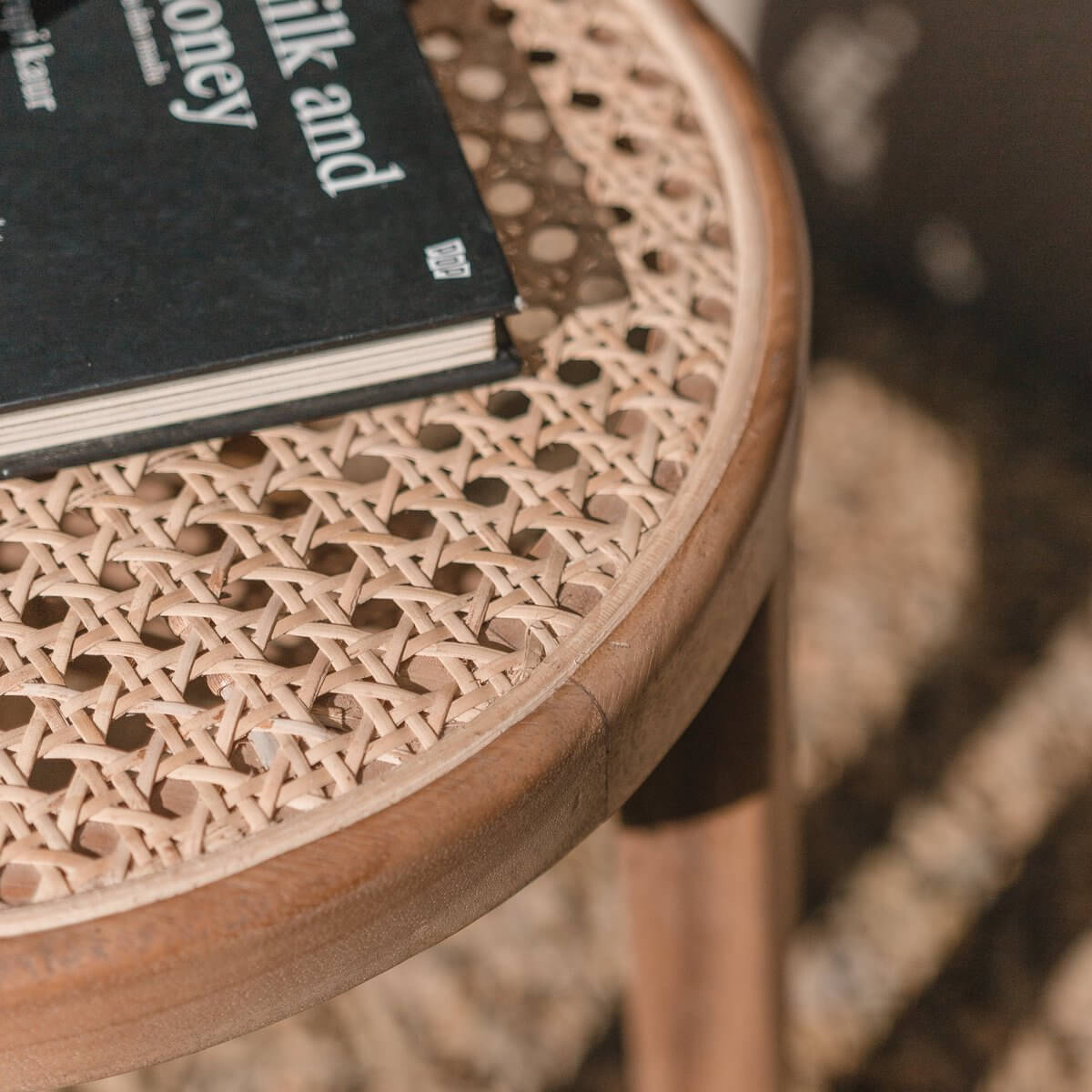 Detail van houten kruk CARAMIN met geperforeerde topping en boek. Elegante toevoeging aan ieder interieur.