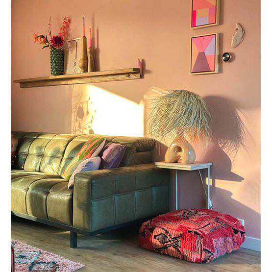 Warme woonkamer met Marokkaans vintage vloerkussen als boho eyecatcher, naast groene bank en trendy decor.