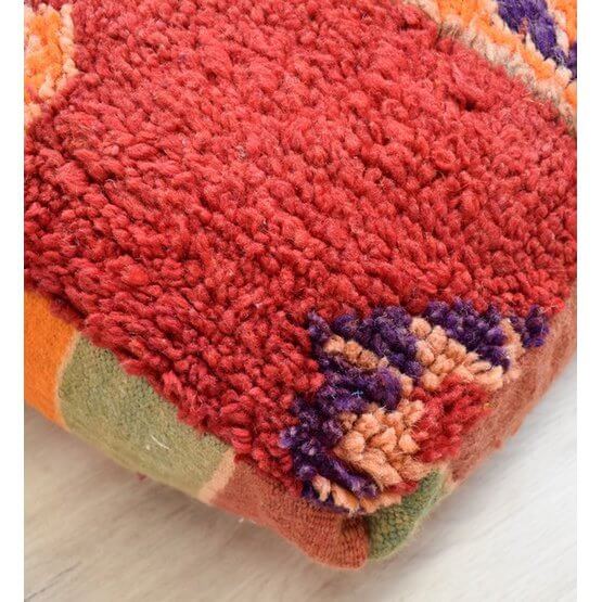 Vintage Marokkaanse vloerkussen gemaakt van berber tapijt, boheemse stijl met unieke patronen in rood en andere kleuren, handgemaakt.