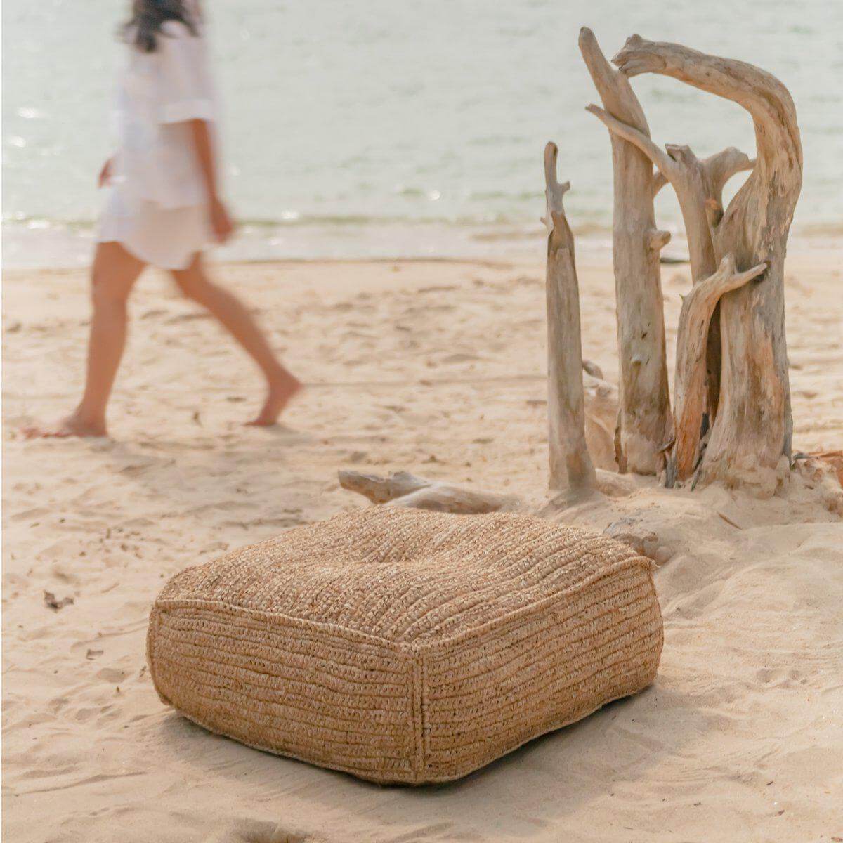 Rustieke raffia zitzak op zandstrand naast drijfhout, ideaal voor ontspanning.