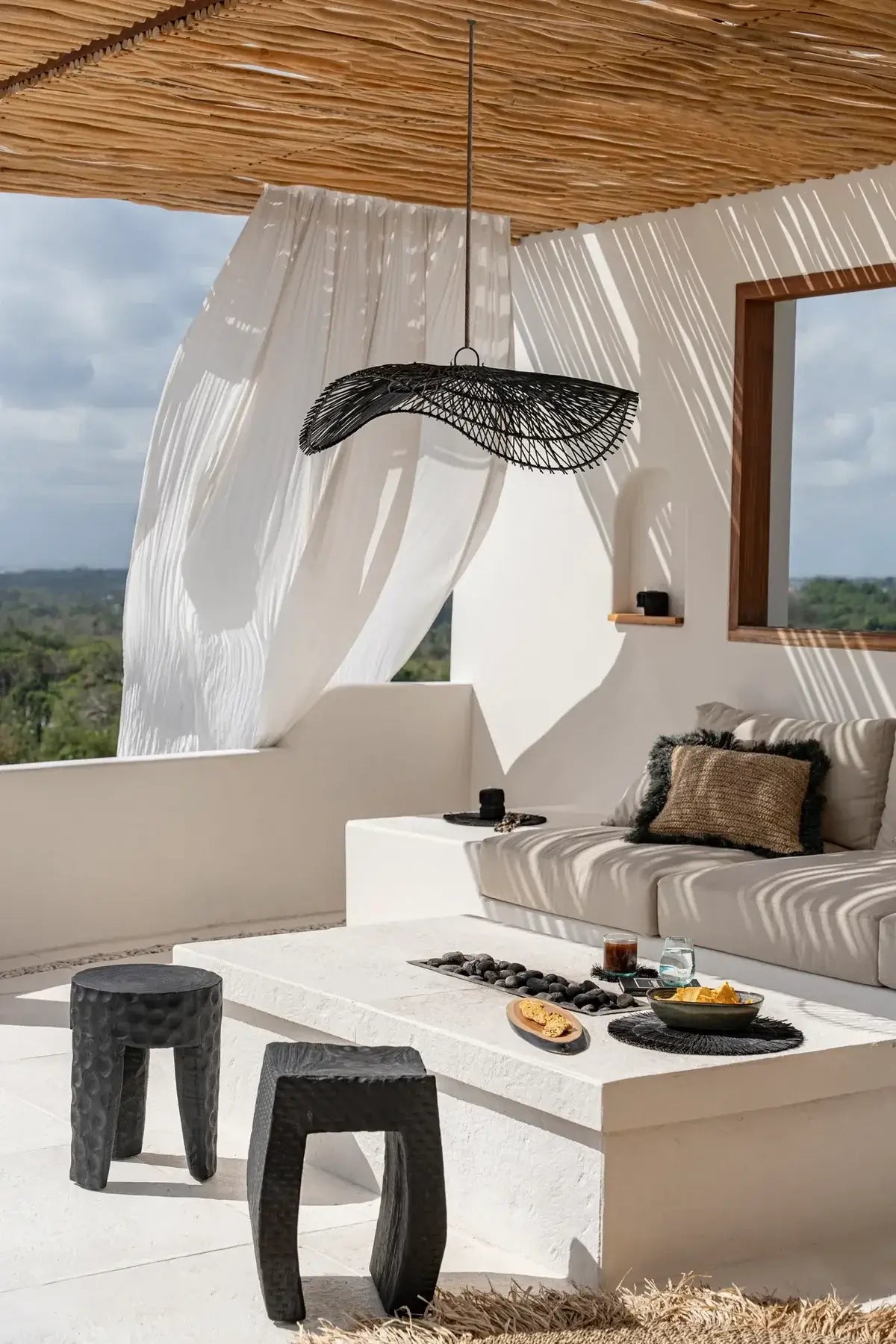 Cozy patio with Rotan Hanglamp Chapeau Zwart, bohemian style decor, wicker furniture, and sunny ambience.