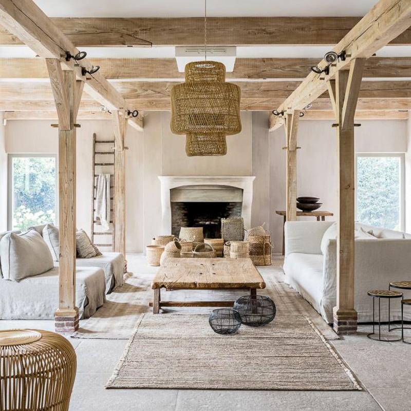 Rustieke woonkamer met houten balken, rotan hanglamp en stijlvolle neutrale inrichting."}