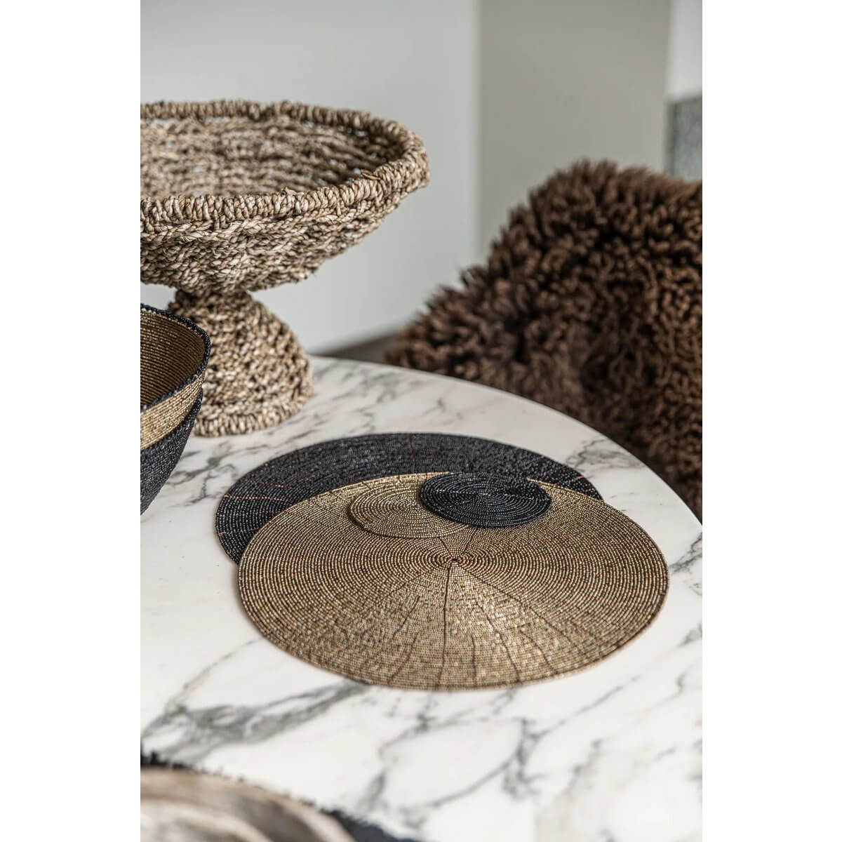 Bohemian black beaded coaster on a marble table, styled with neutral decor for a chic Boho dining setup.