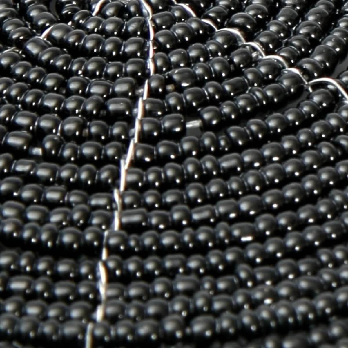Close-up of The Beaded Coaster - Zwart, showcasing intricate black beads for a Bohemian table setting by Bazar Bizar Living.