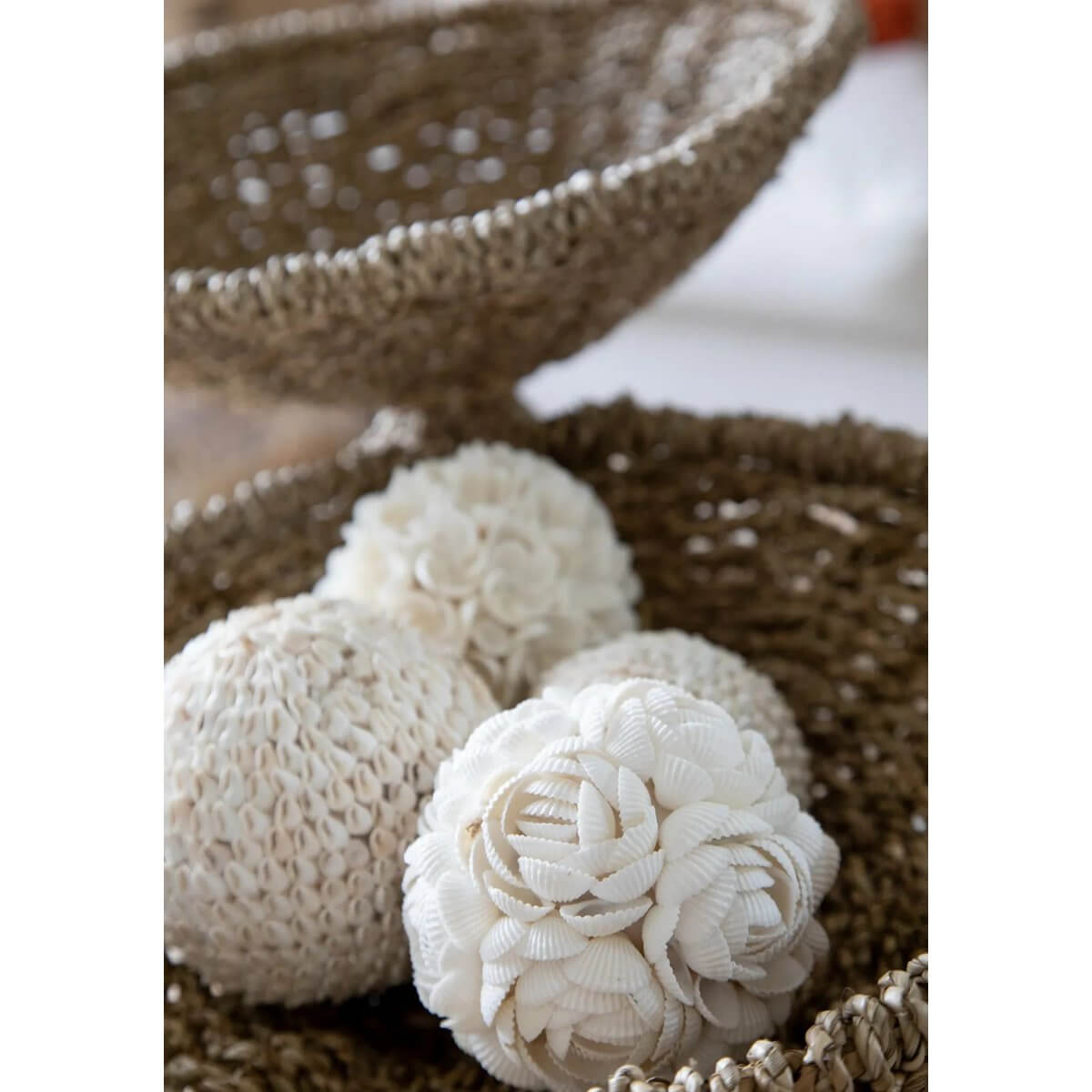 Handcrafted white shell balls in rustic basket, perfect for bohemian decor, made by Balinese artisans, ideal for displaying or hanging.