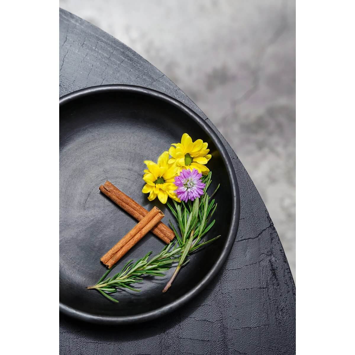 Chic Bohemian black ceramic plate with colorful flowers and cinnamon sticks, perfect for stylish table settings.