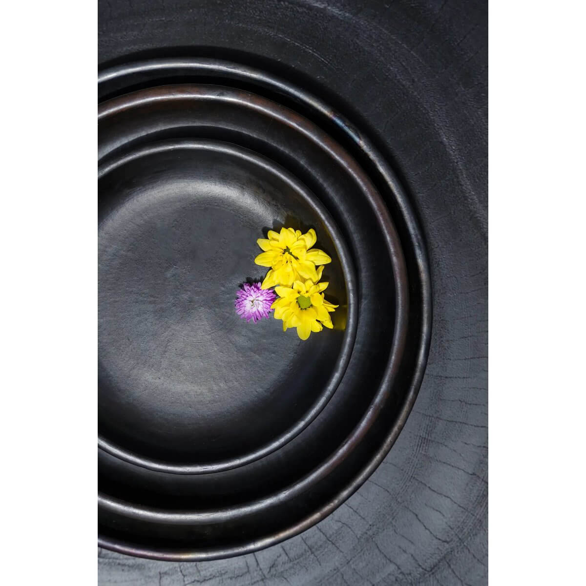 Bohemian black terracotta plate set from Bazar Bizar Living, featuring yellow and purple flowers, enhancing brunch table beauty.