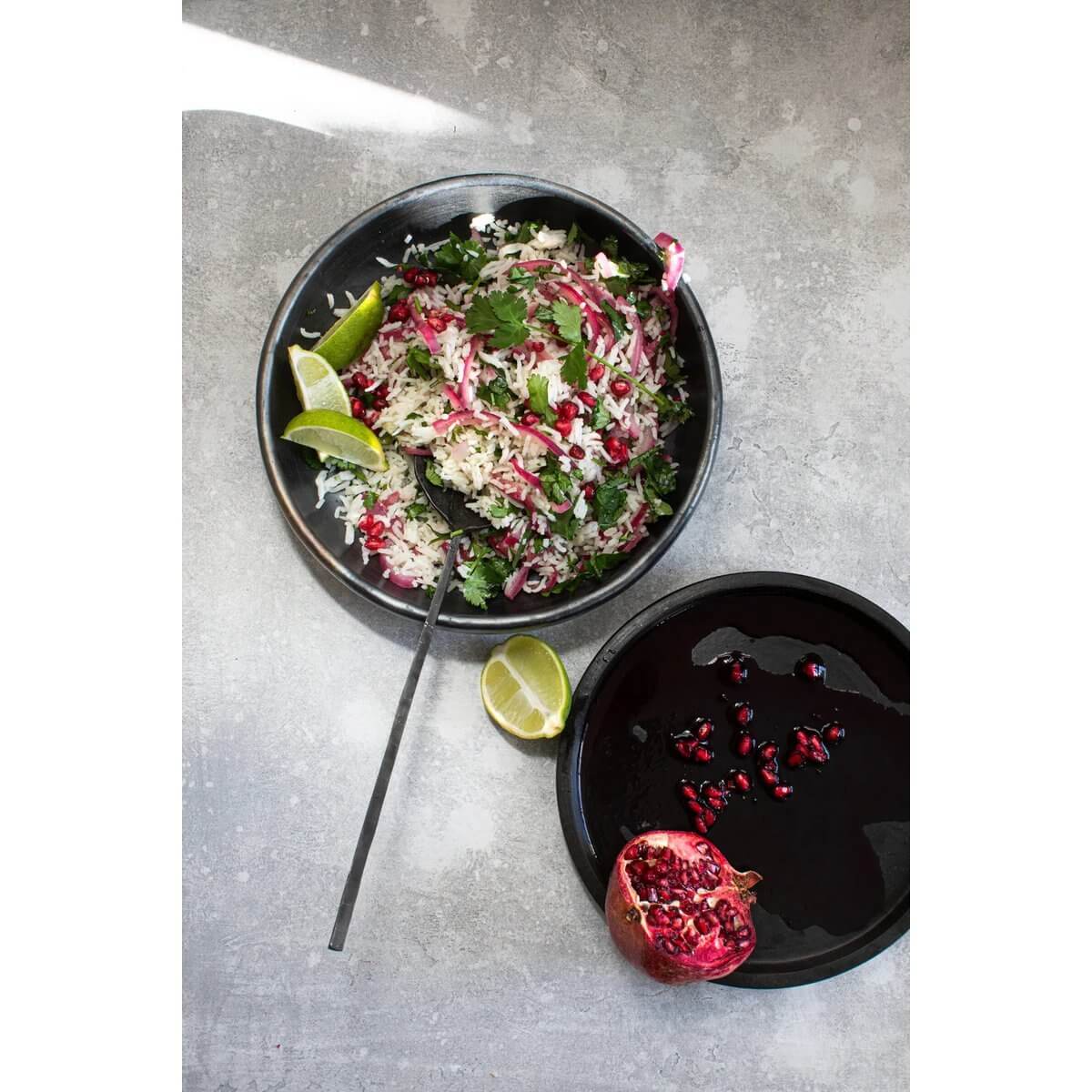 Bohemian style black terracotta deep plate with vibrant salad and lime slices, perfect for a stylish brunch or dinner setting.