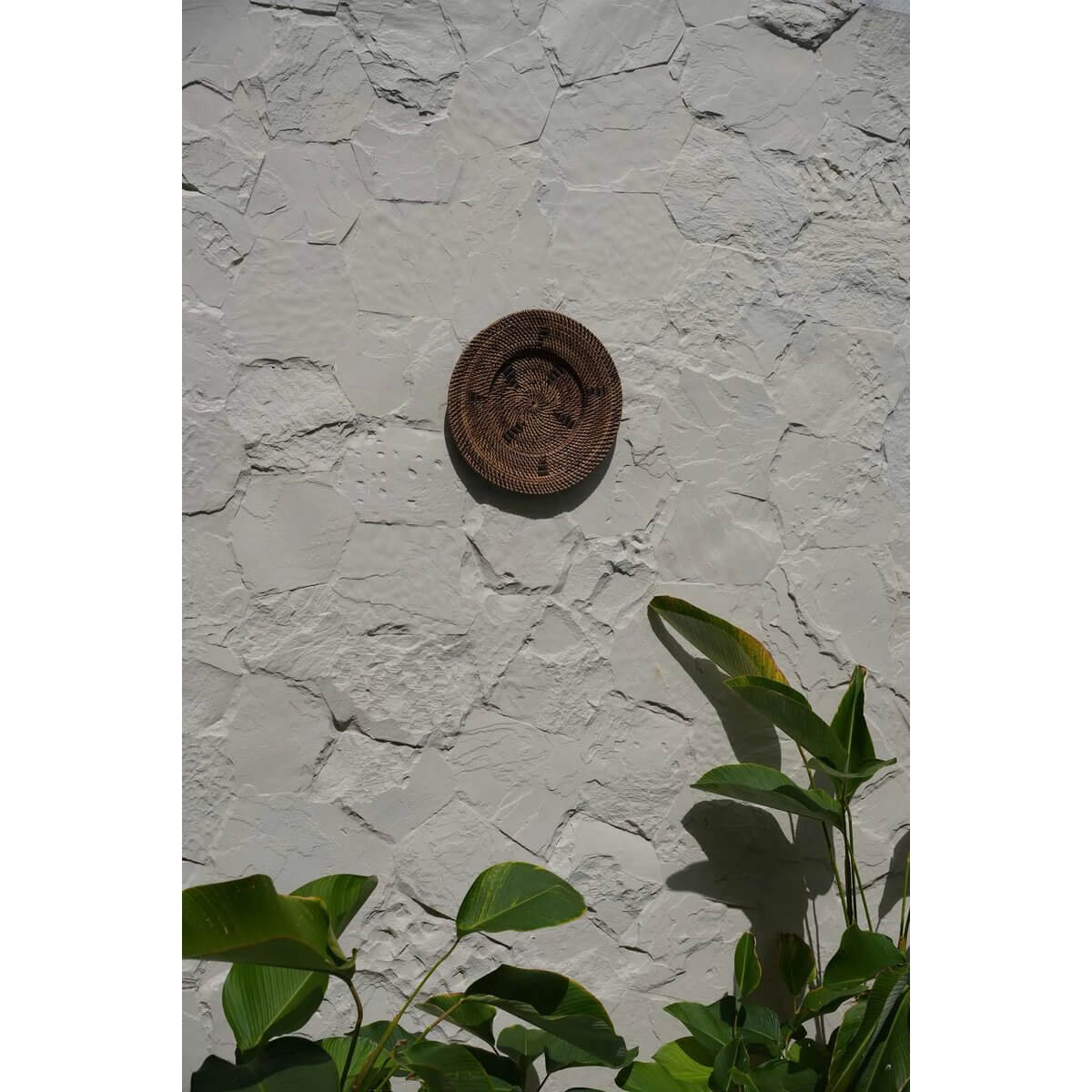 Alt Tag: Handgeweven bruin rotan bord met zwarte grafische details aan witte muur, uniek etnisch wandmeubel voor interieur, Bazar Bizar.