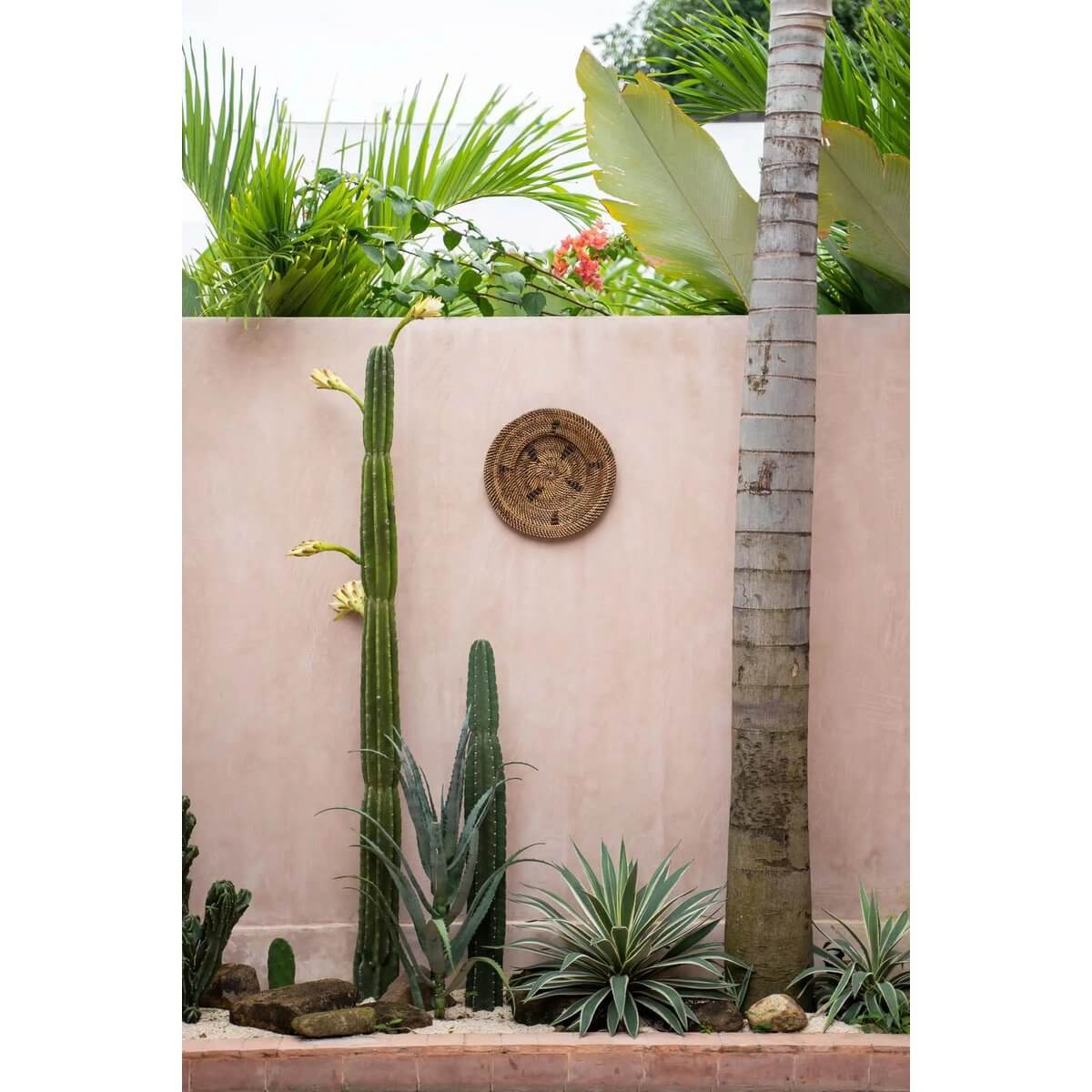 Houten gevel met de Jasmine Bord - Bruin, een zwart grafisch wanddisplay van Bazar Bizar Living, met tropische planten op de achtergrond.