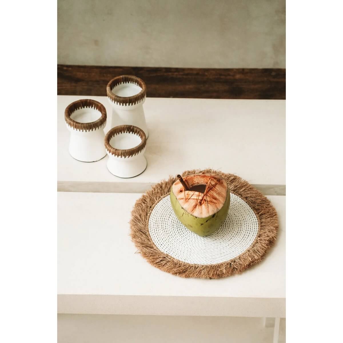 The Pretty Candle Holder in white terracotta with raffia accents adds a bohemian touch to any space. Available in three heights.