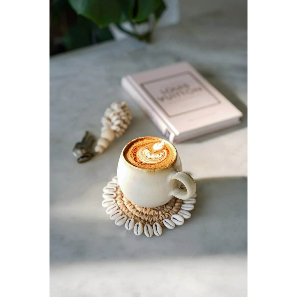 Bohemian Raffia Shell Coaster with coffee, showcasing traditional Balinese design, beautifully adorned with cowrie shells by Bazar Bizar Living.