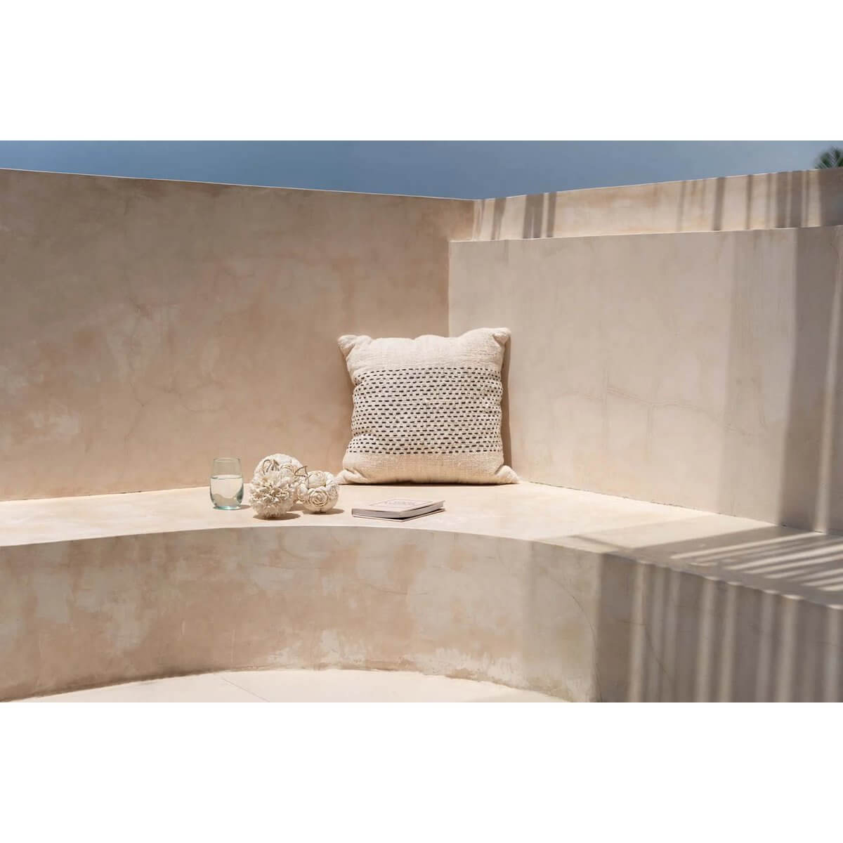 Bohemian decor with a handcrafted rose shell ball and cushion on a sunlit stone terrace.