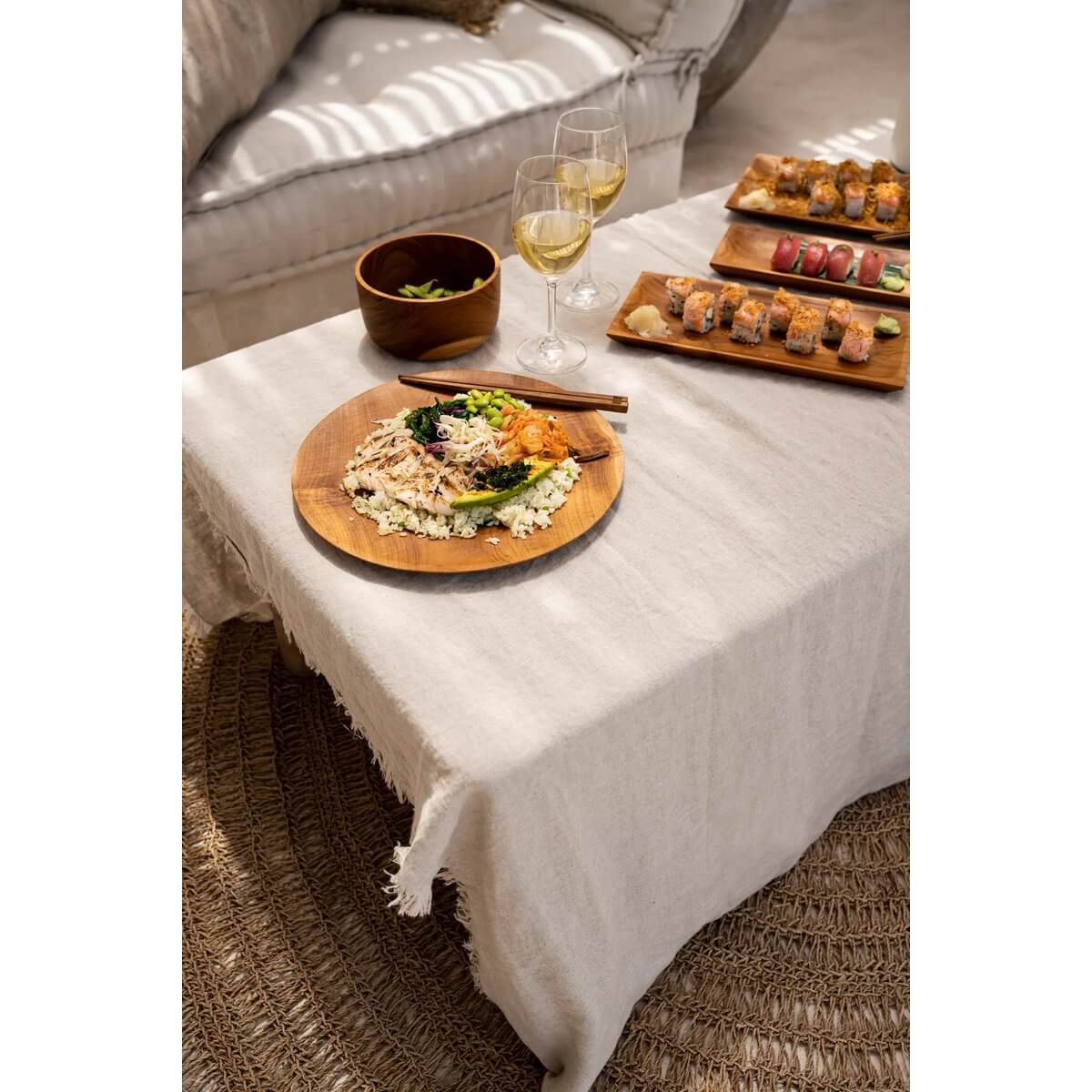 Stylish bohemian dining setup with The Teak Root Round Plate serving a dish, surrounded by elegant decor and wine glasses.