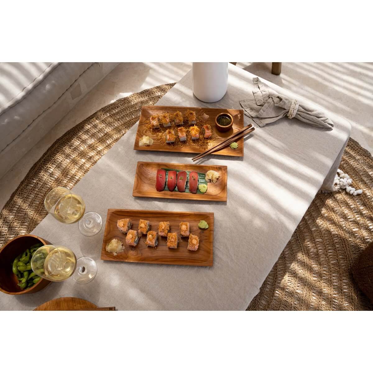 Bohemian style dining with sushi on teak root plates by Bazar Bizar Living, featuring rustic charm and elegance.