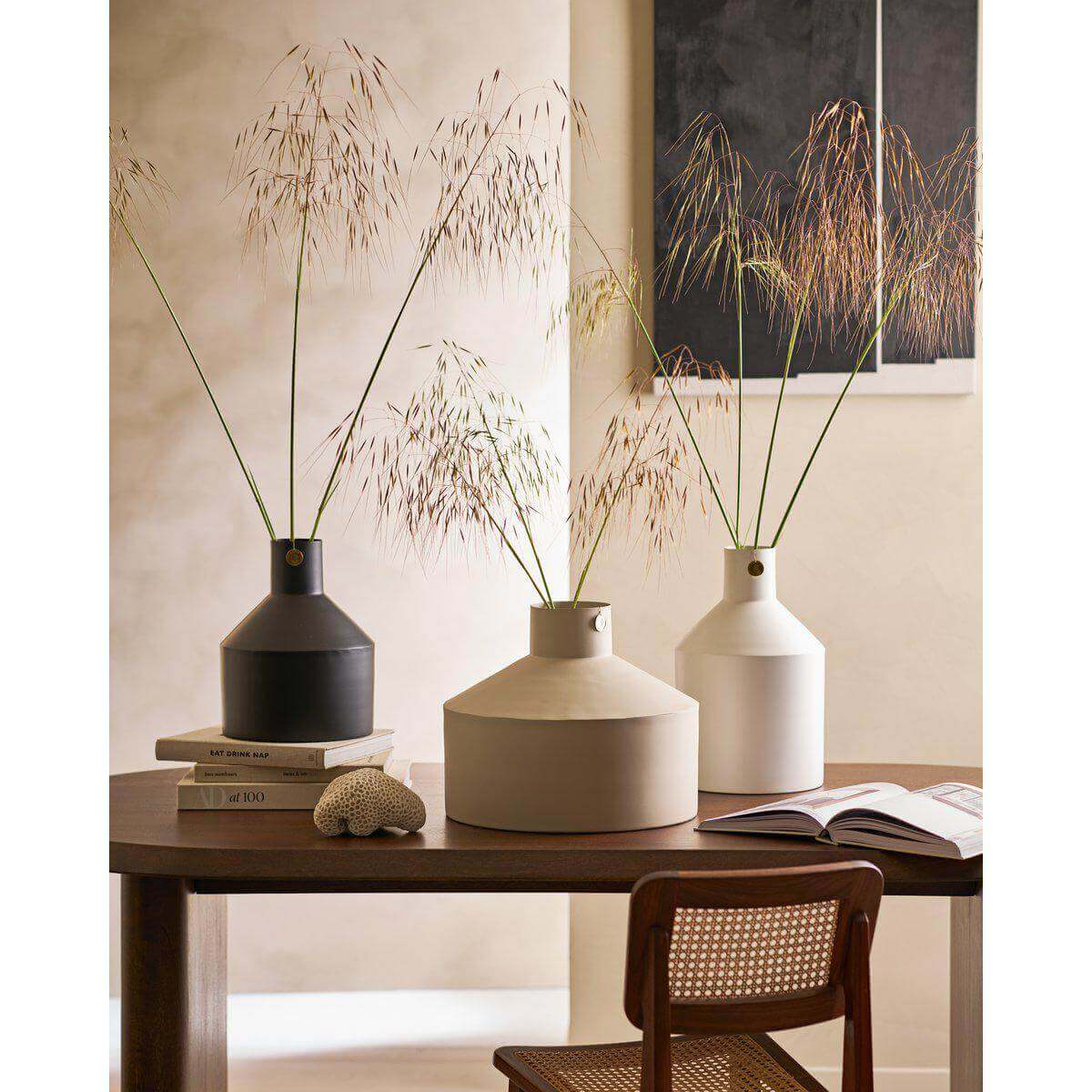 Stijlvolle metalen vazen op tafel met droogbloemen in modern interieur, ideaal voor decoratie en designliefhebbers.