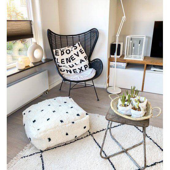 Gezellige woonkamer met een gestippeld vloerkussen, comfortabele fauteuil en stijlvol decor voor een warme sfeer.