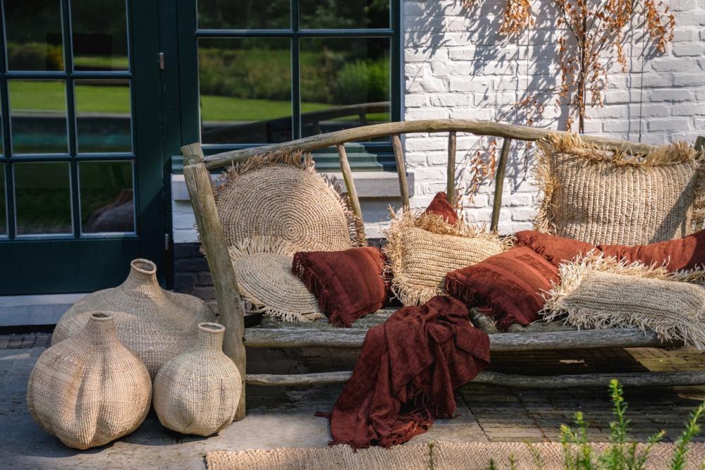 Gezellig terras met boho stijl, inclusief bordeaux fluwelen kussenhoezen en rustieke decoraties. Perfect voor binnen en buiten textuur.