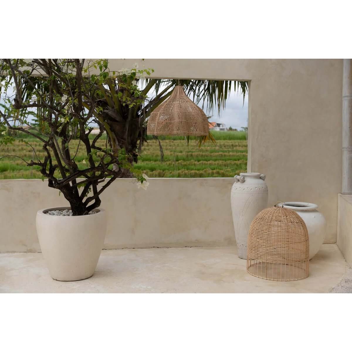 Bohemian style rattan lamp in a serene outdoor setting with pottery and greenery, perfect for unique indoor and undercover spaces.