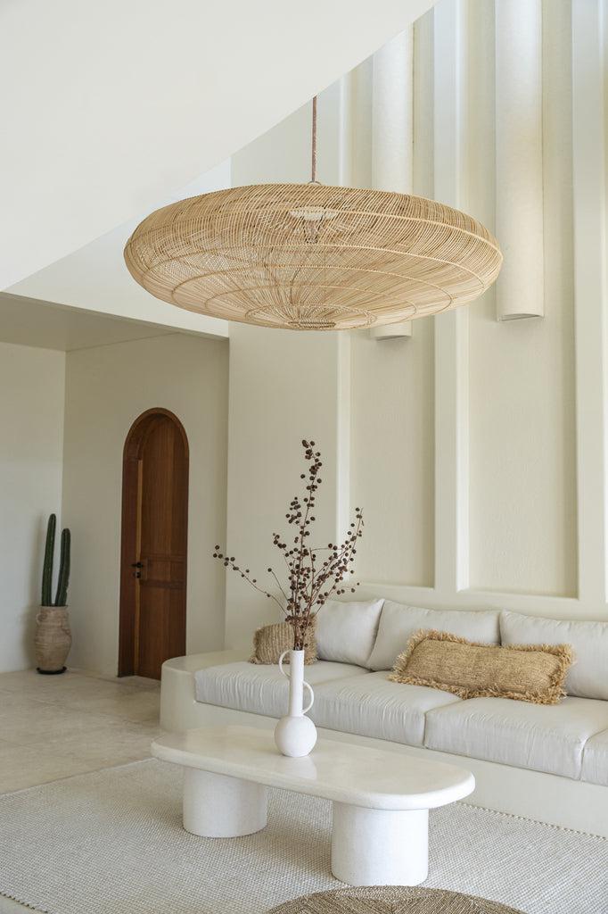 Lichte woonkamer met natuurlijke raffia kussen op witte bank, handgeweven in Indonesië, met modern boho chic interieurdesign.