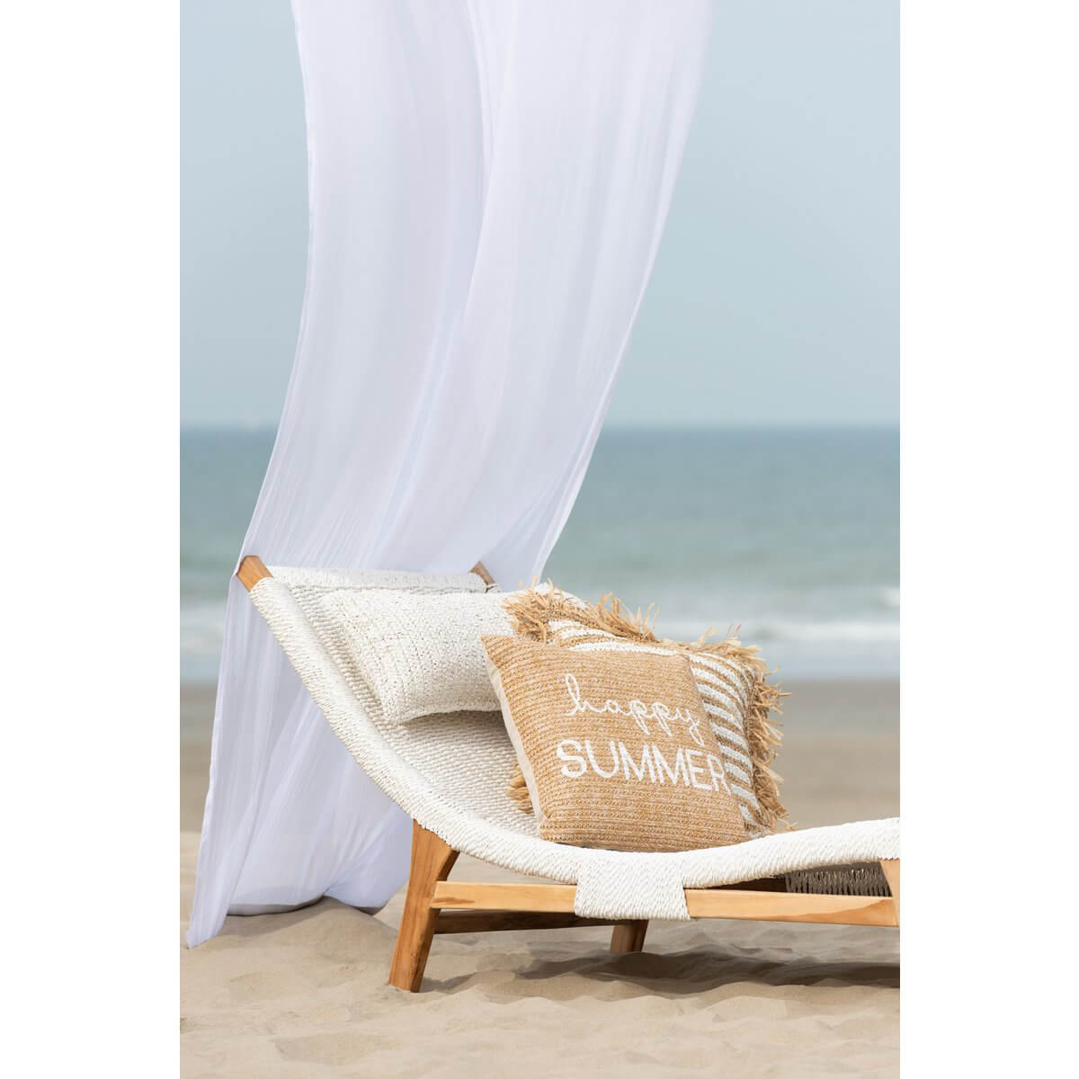 Witte J-Line ligzetel met kussen op strand met woorden 'happy summer' op kussen, luxe comfort en stijlvol design.