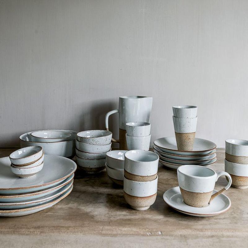 Collectie van keramisch servies met zandglazuur, inclusief kommen en bekers, perfect voor yoghurt of snacks op filmavonden. Geschikt voor vaatwasser.