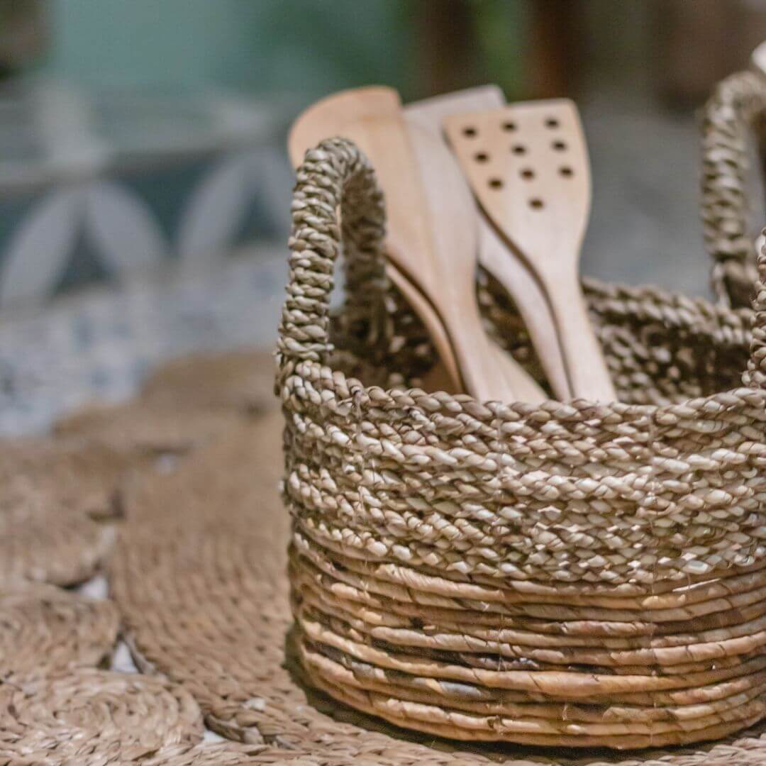 Handgemaakte opbergmand KUTUS van zeegras en bananenvezel met houten keukengerei, duurzaam en decoratief in elke keuken.