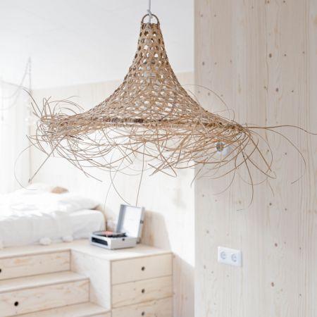 Rotan hanglamp Yao met bohemian uitstraling in slaapkamer, hangend boven houten meubilair voor een Ibiza-sfeer in huis.