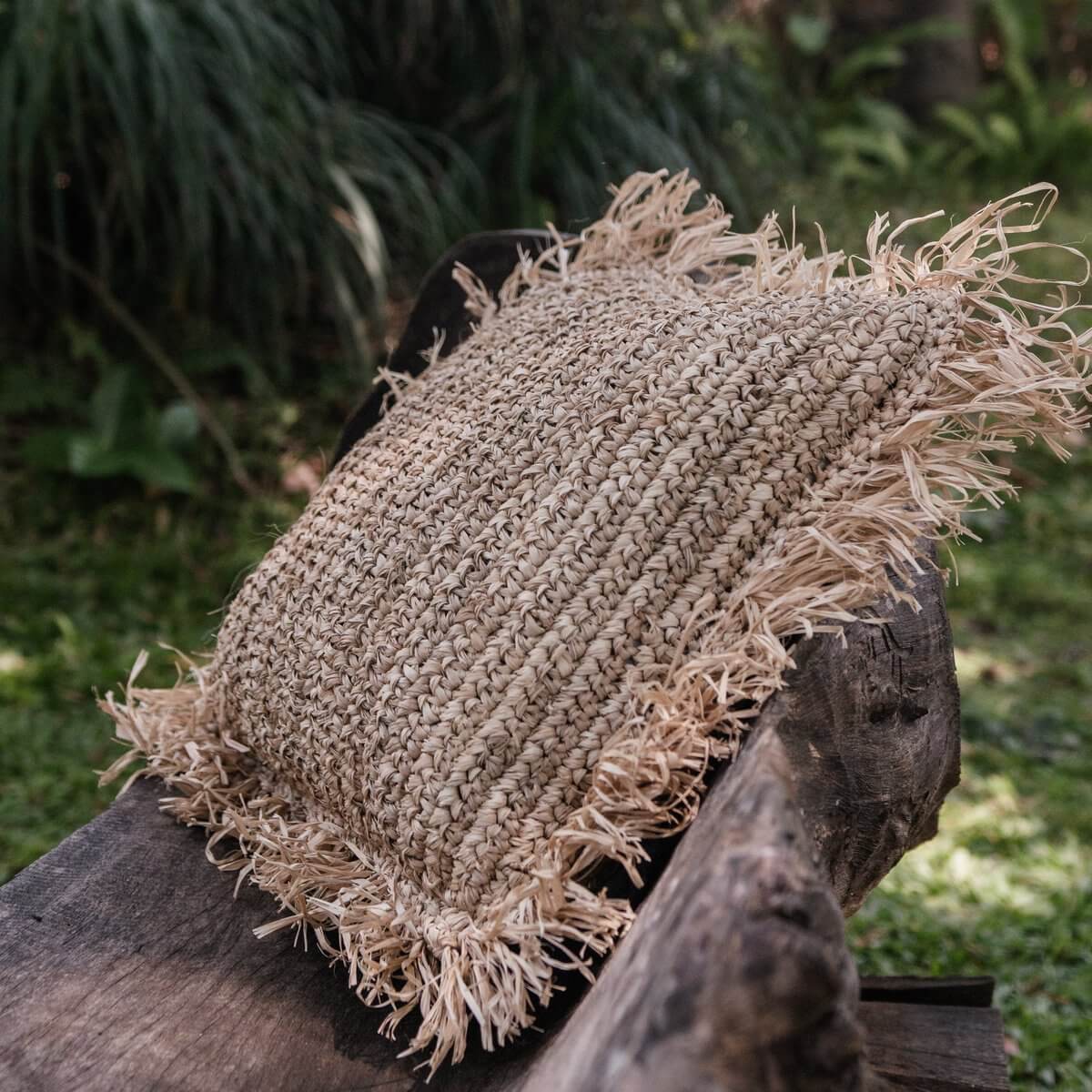 Natuurlijk decoratief kussen GANDI van raffia op houten bankje, perfect voor sofa of bed, fairtrade en handgemaakt.