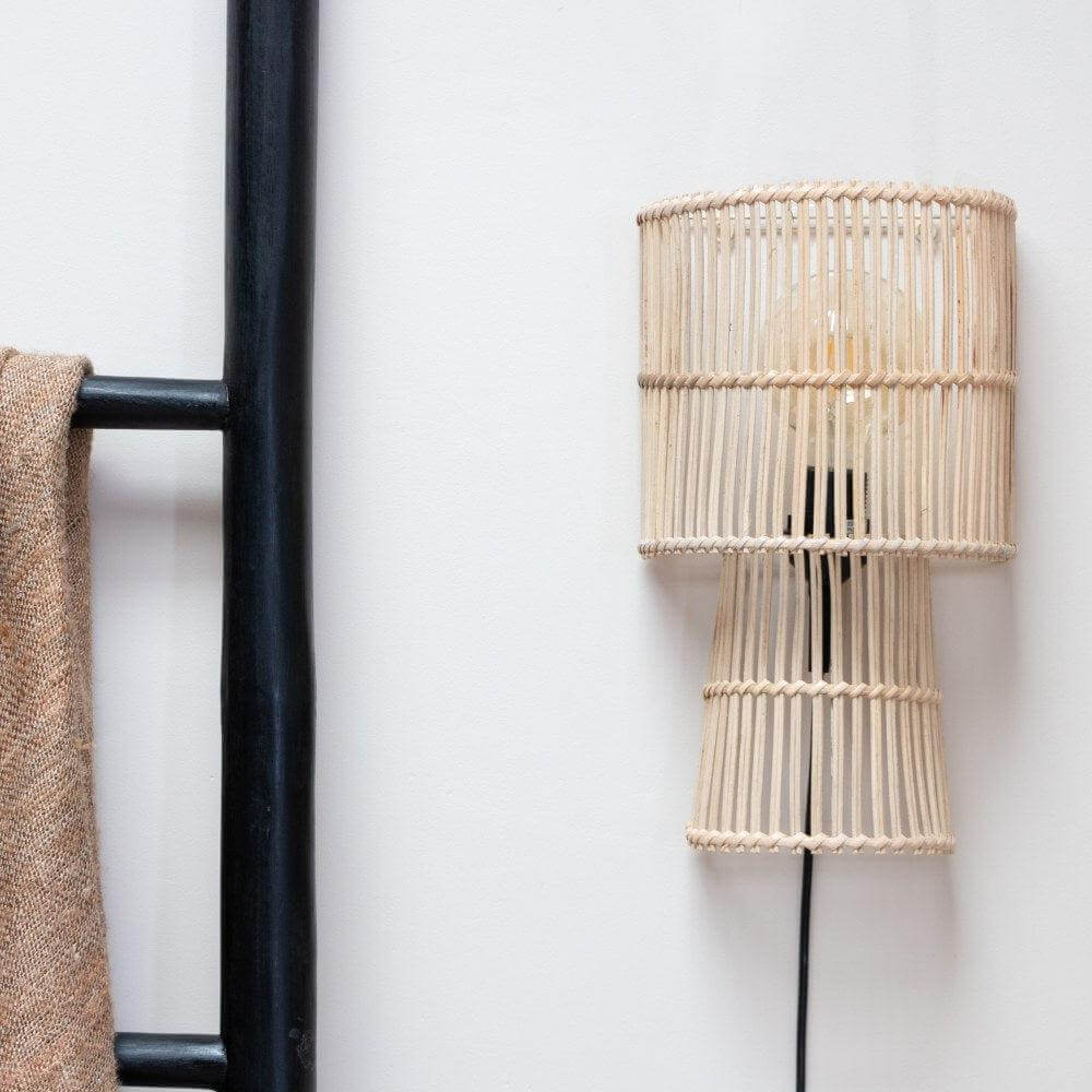 Stijlvolle wandlamp rotan Misa naast zwarte ladder en bruine deken, perfect voor een natuurlijke uitstraling in de slaapkamer.